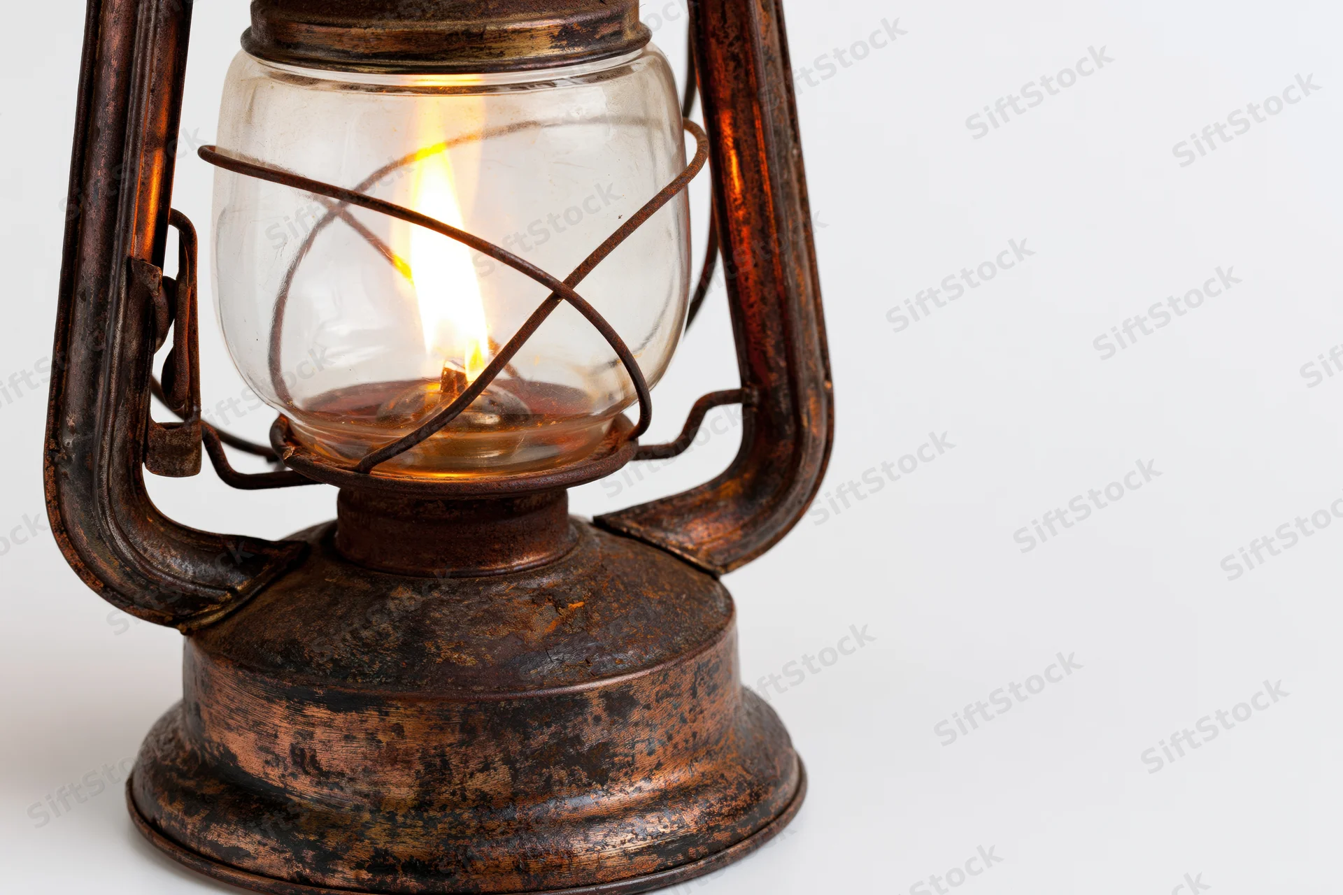 Antique kerosene lantern with lit flame glowing inside, isolated on white background