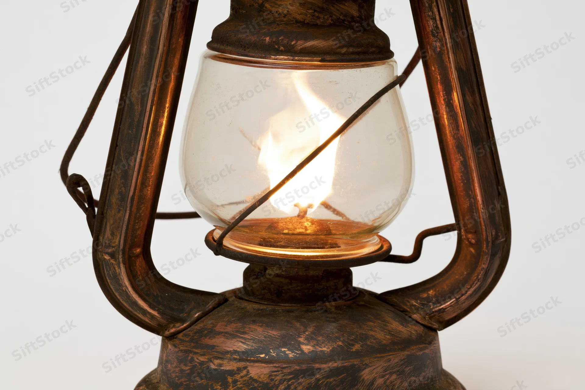 Antique kerosene lantern with lit flame glowing inside, isolated on white background
