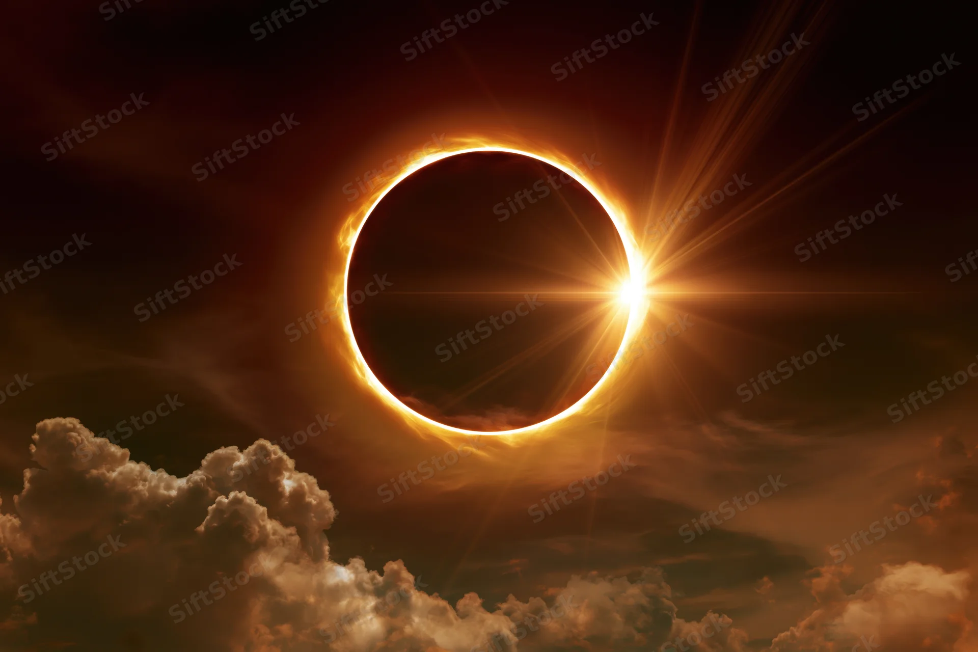 Annular solar eclipse at peak totality with moon centered and corona glowing against cloudy sky