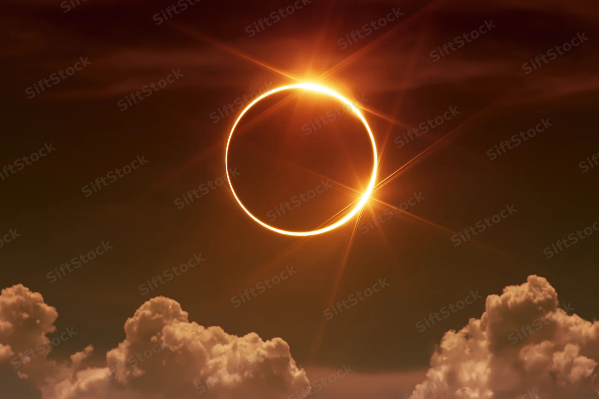 Annular solar eclipse at peak totality with moon centered and ring of light visible above clouds
