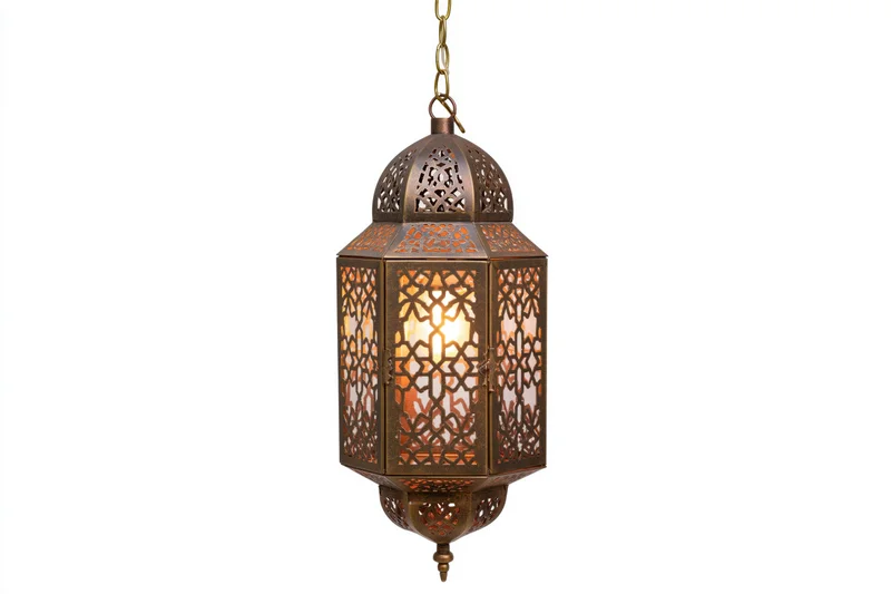 Antique moroccan lantern hanging from brass chain with intricate cutout patterns glowing warmly against white background