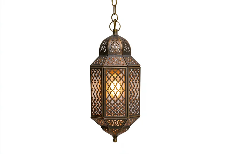Antique moroccan lantern hanging from a brass chain with intricate cutout patterns glowing warmly against white background