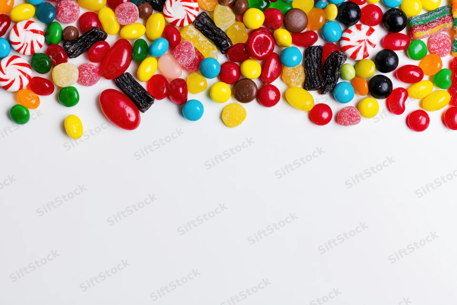 Assorted candies scattered across white surface with copyspace below