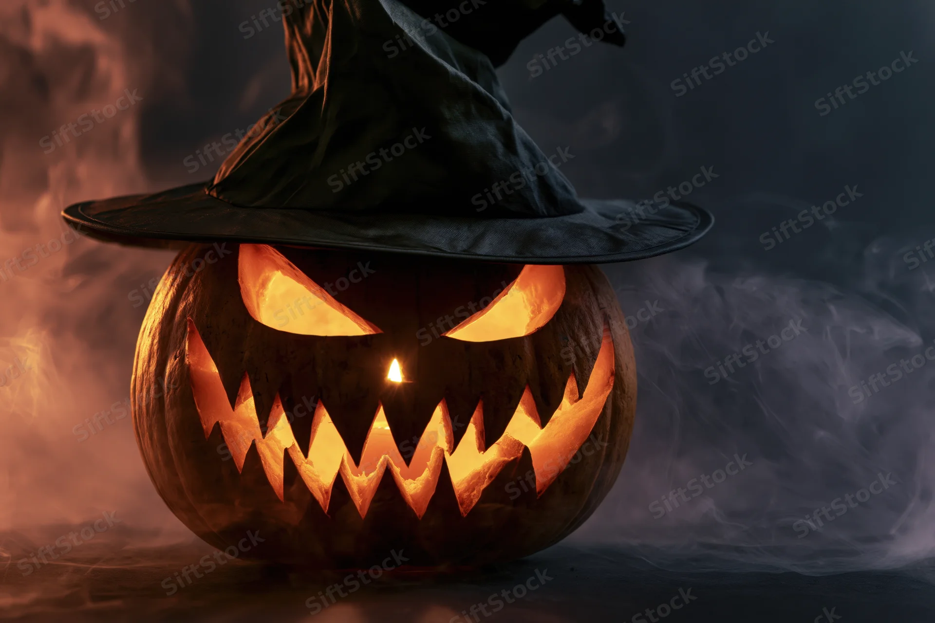 Carved jack-o-lantern with glowing eyes and jagged grin wearing a black witch hat in smoky dark setting