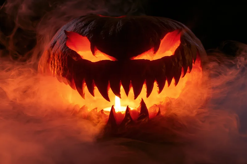 Carved jack-o-lantern with jagged teeth glowing in smoke at night