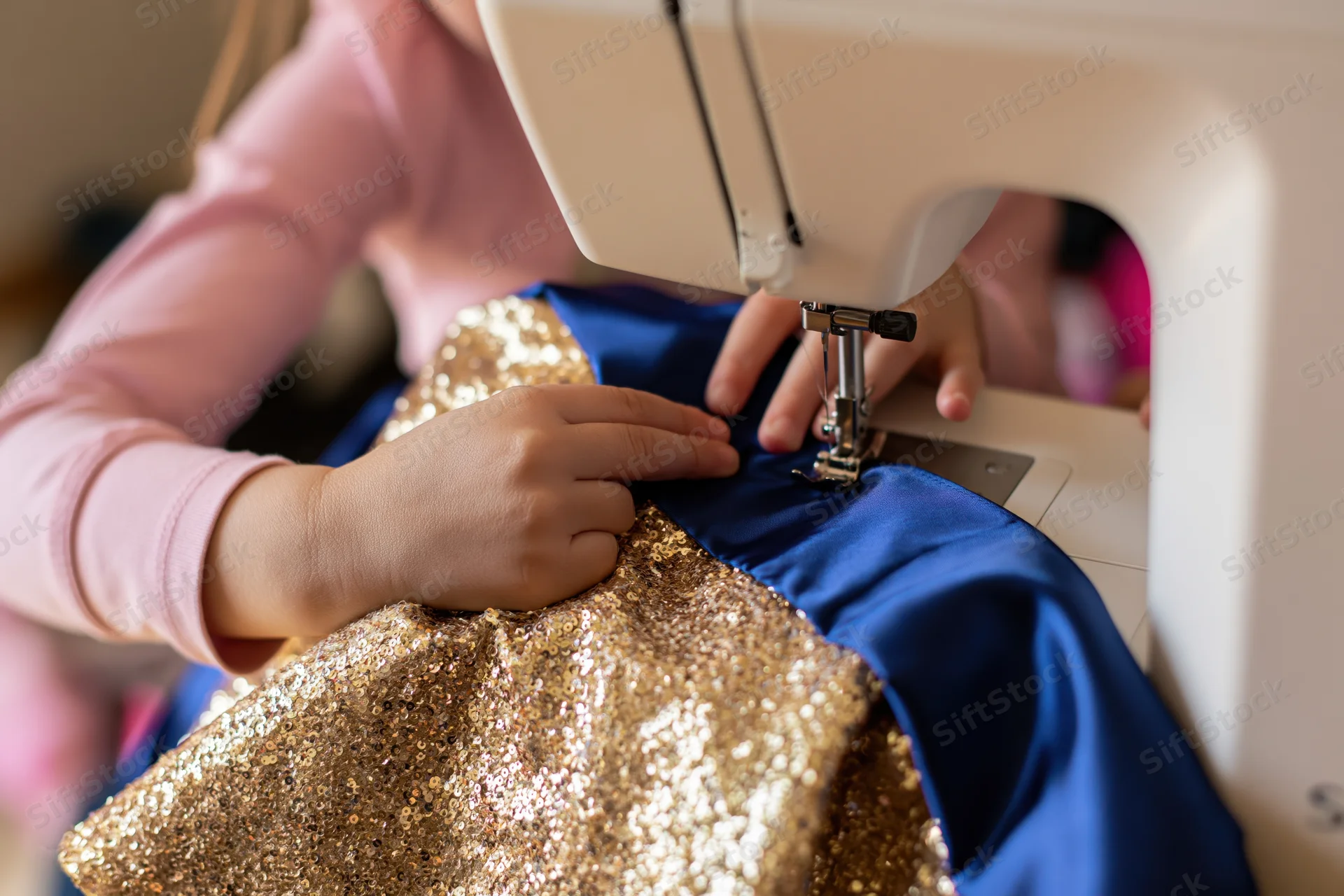 Child guiding gold glitter and blue fabric under sewing machine needle