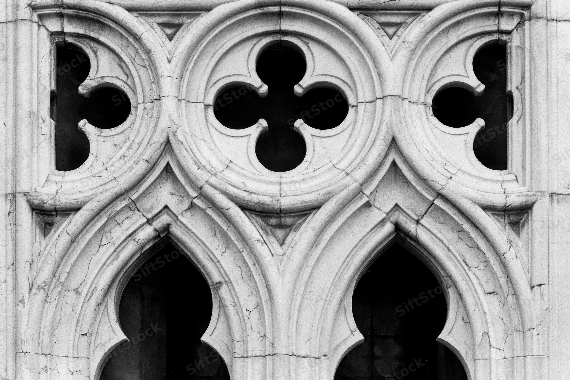 Close-up of gothic stone tracery with quatrefoil and pointed arches on a church facade