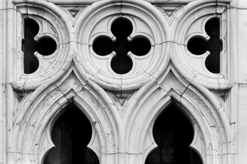 Close-up of gothic stone tracery with quatrefoil and pointed arches on a church facade