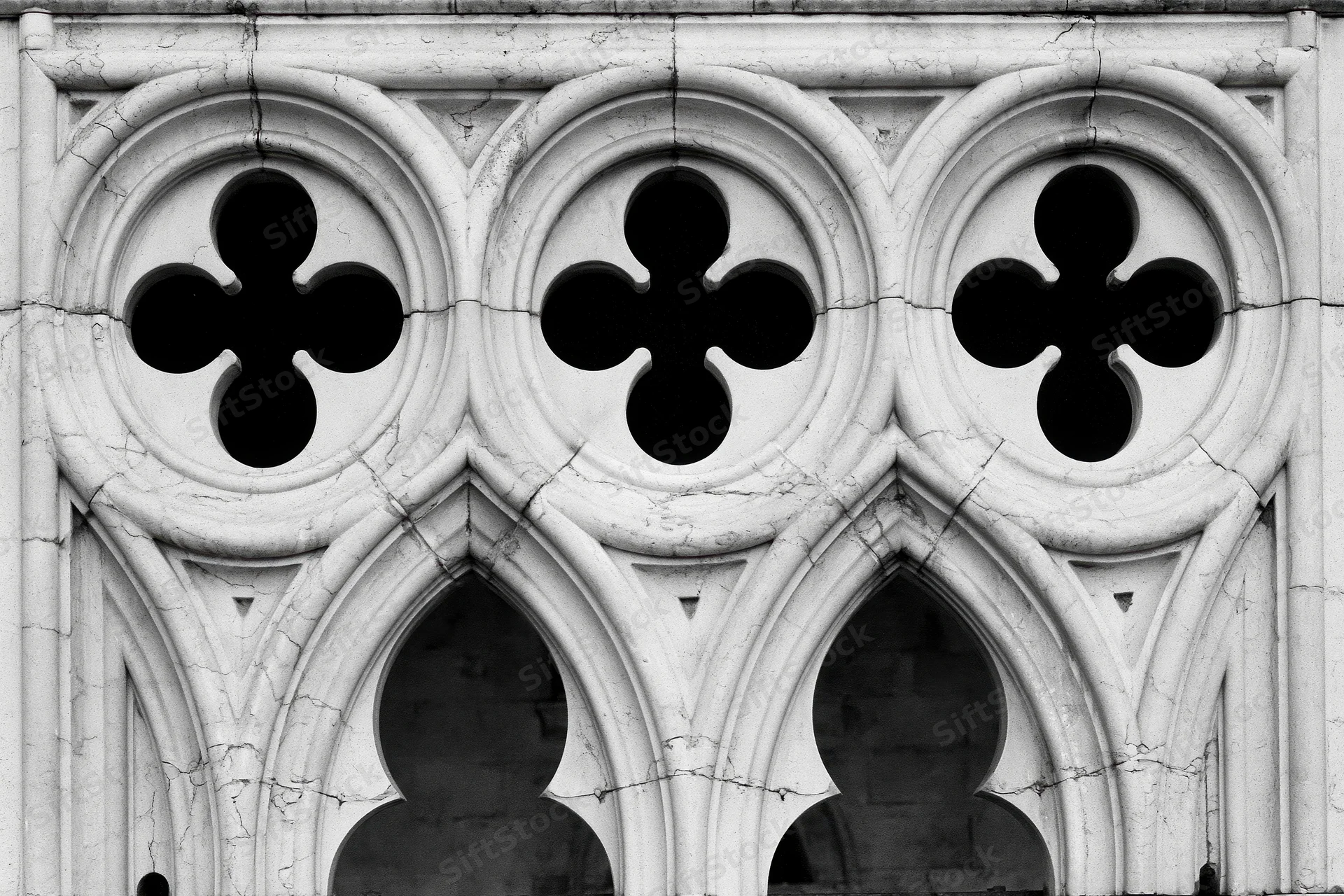 Close-up of gothic stone tracery with quatrefoil patterns and pointed arches on a church facade