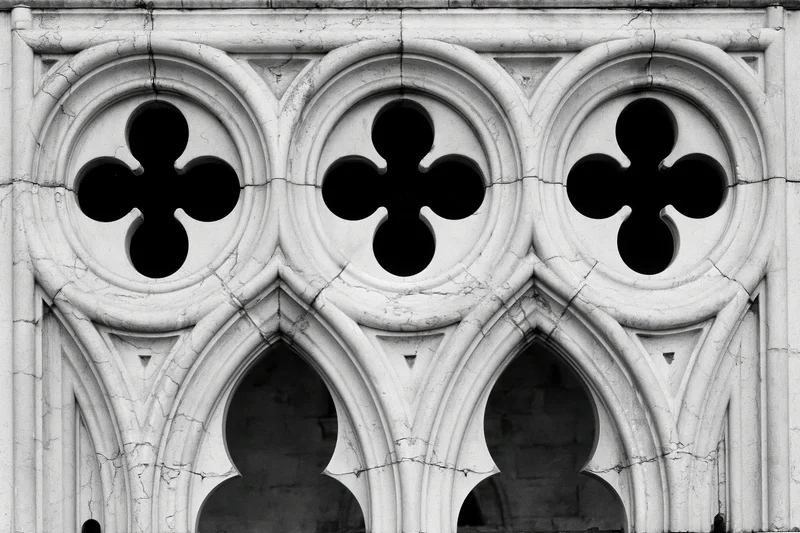 Close-up of gothic stone tracery with quatrefoil patterns and pointed arches on a church facade