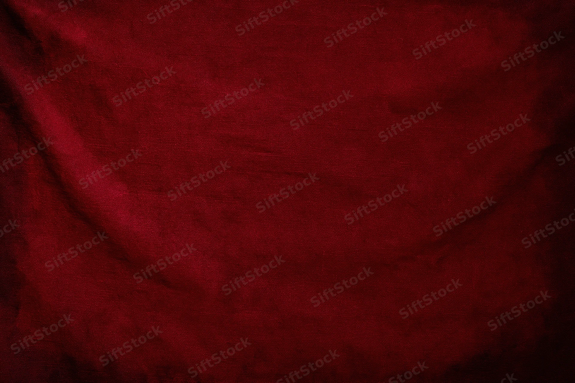 Close-up of worn red fabric texture with visible weave and folds