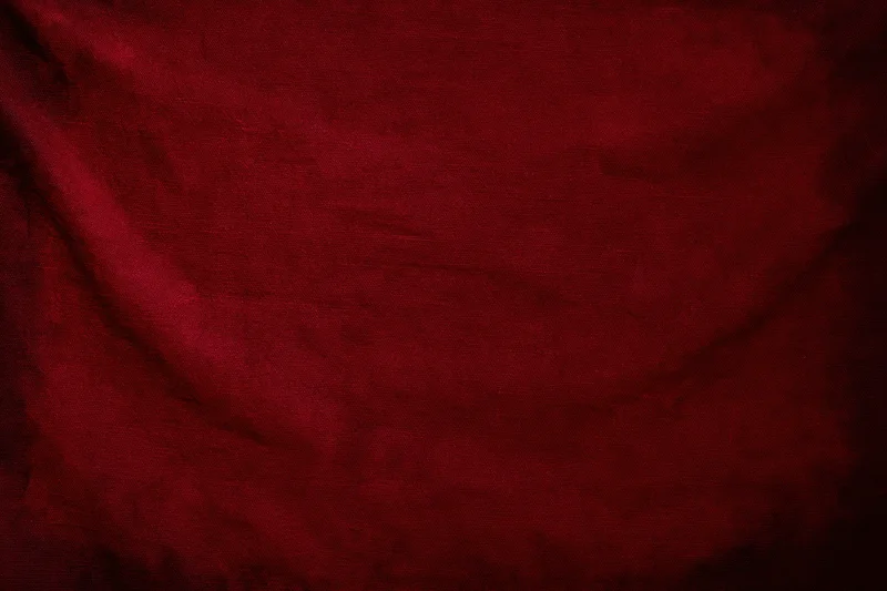 Close-up of worn red fabric texture with visible weave and folds