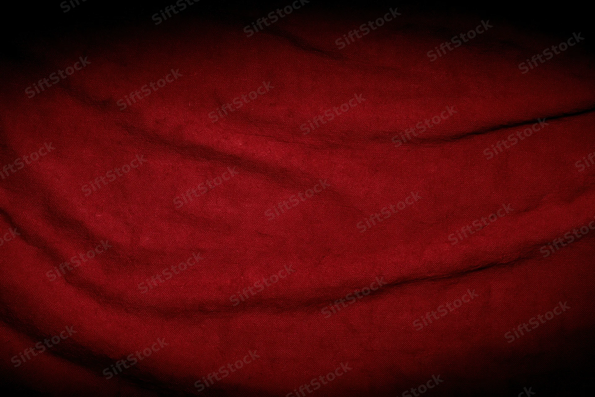 Close-up of worn red fabric with wrinkles and shadows