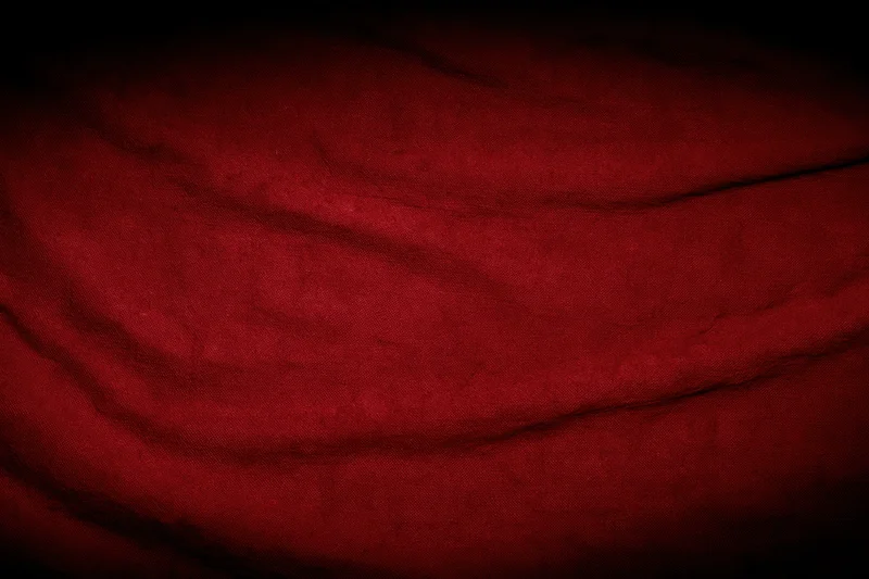 Close-up of worn red fabric with wrinkles and shadows