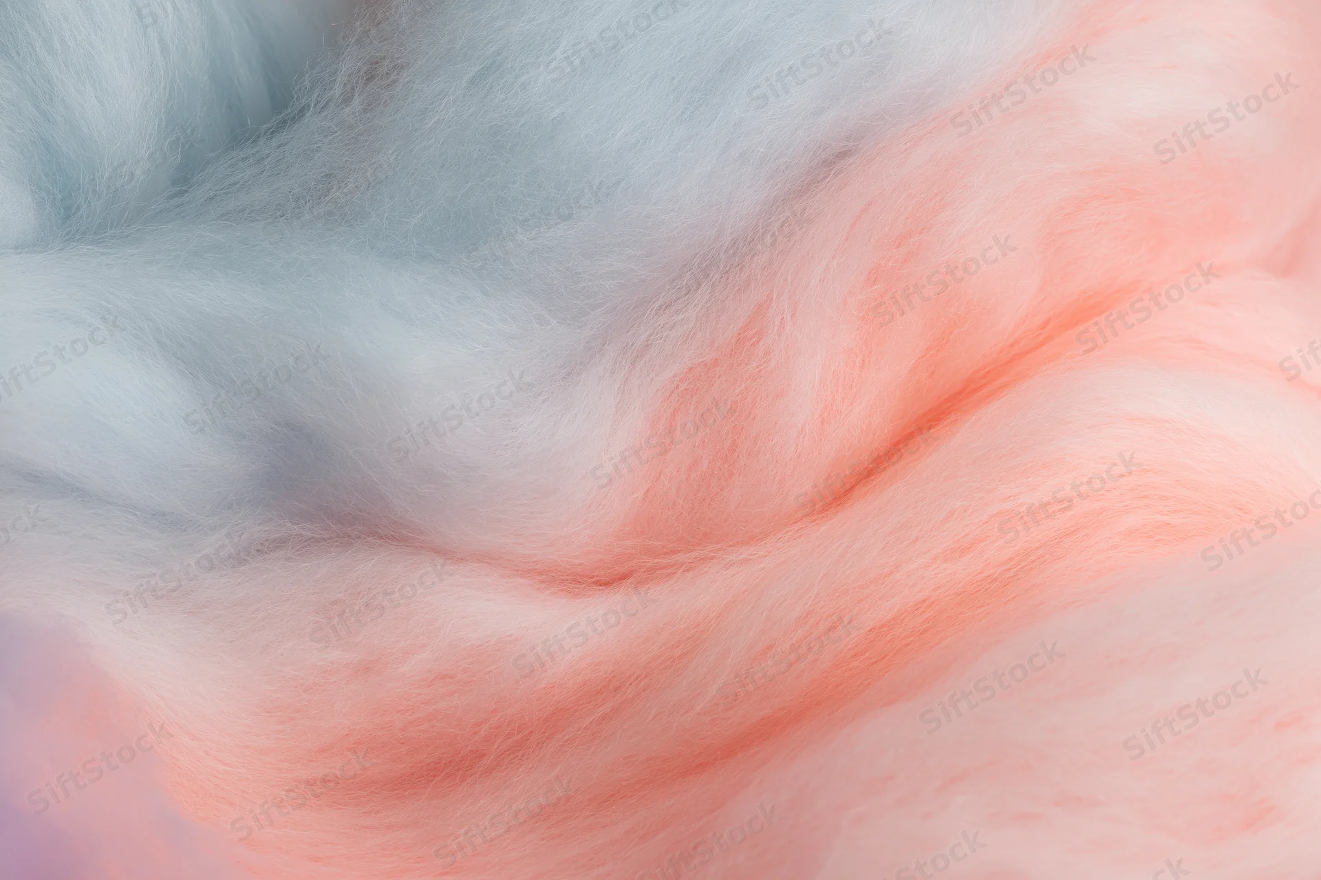 Close-up of cotton candy with soft pink and blue fibers filling the frame