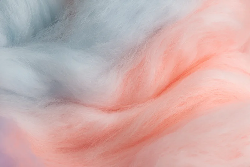 Close-up of cotton candy with soft pink and blue fibers filling the frame