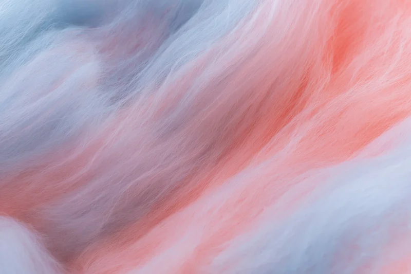 Close-up of cotton candy fibers swirling in soft pink and blue hues filling the frame