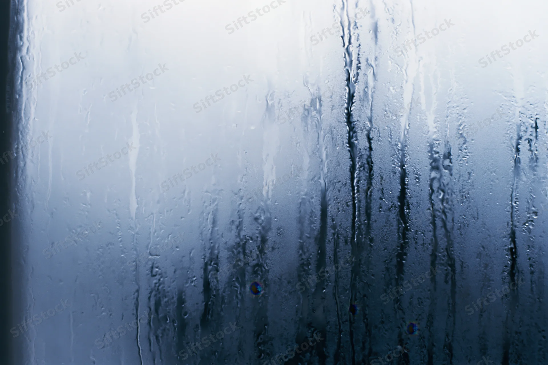 Close-up of fogged glass window with condensation streaks and water droplets
