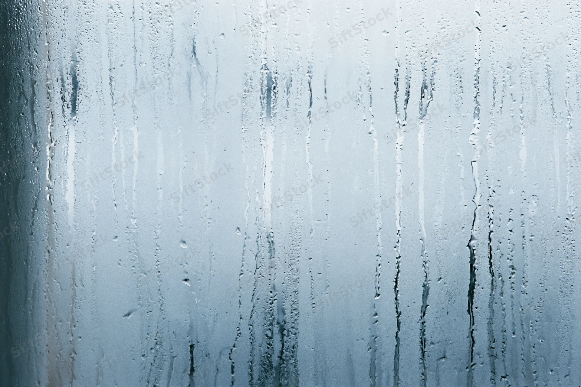 Close-up of condensation streaks on a fogged glass window surface