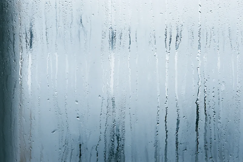 Close-up of condensation streaks on a fogged glass window surface