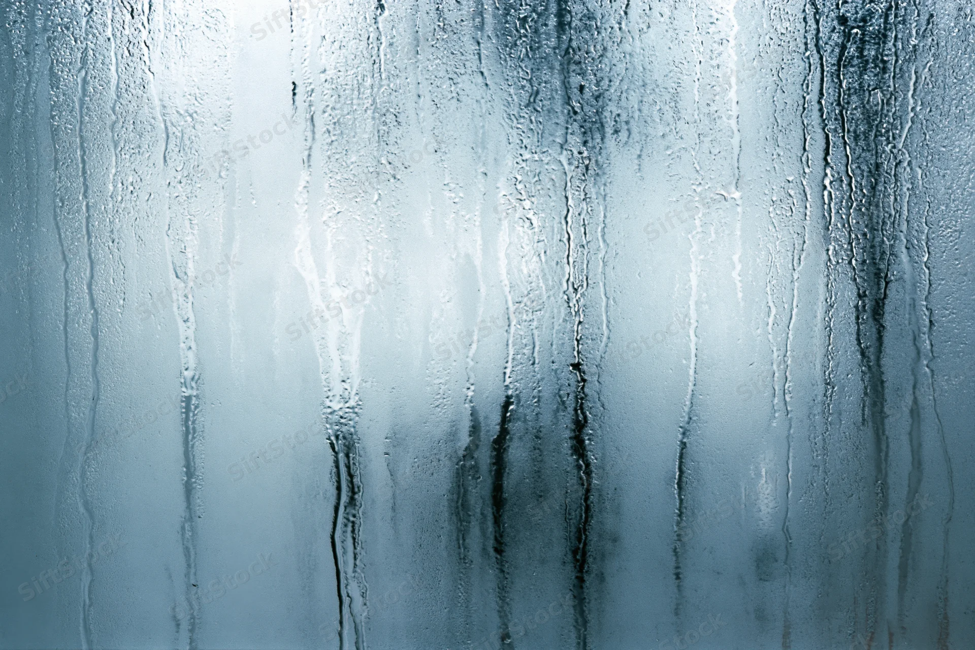 Close-up of condensation streaks on a fogged glass window surface