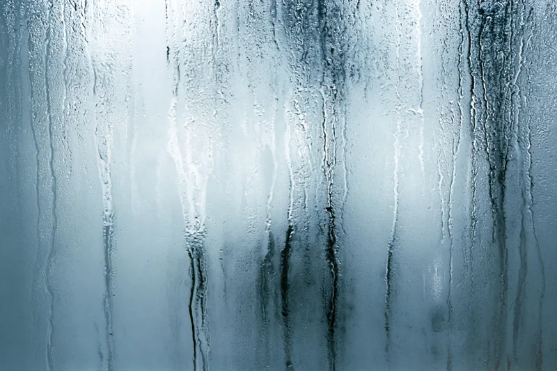 Close-up of condensation streaks on a fogged glass window surface