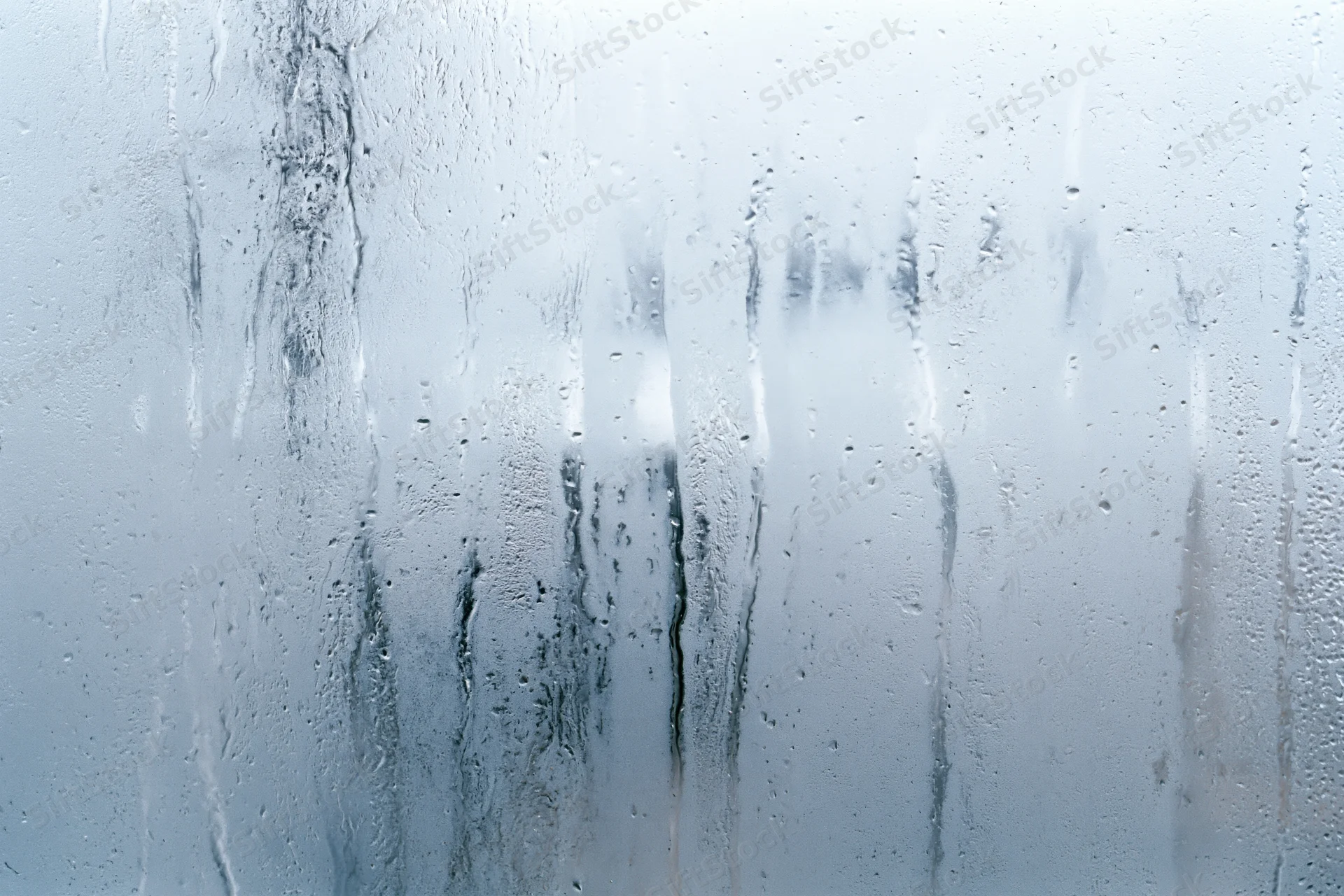 Close-up of fogged glass window with condensation streaks and water droplets