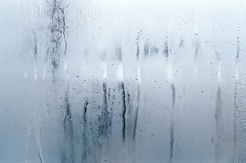 Close-up of fogged glass window with condensation streaks and water droplets