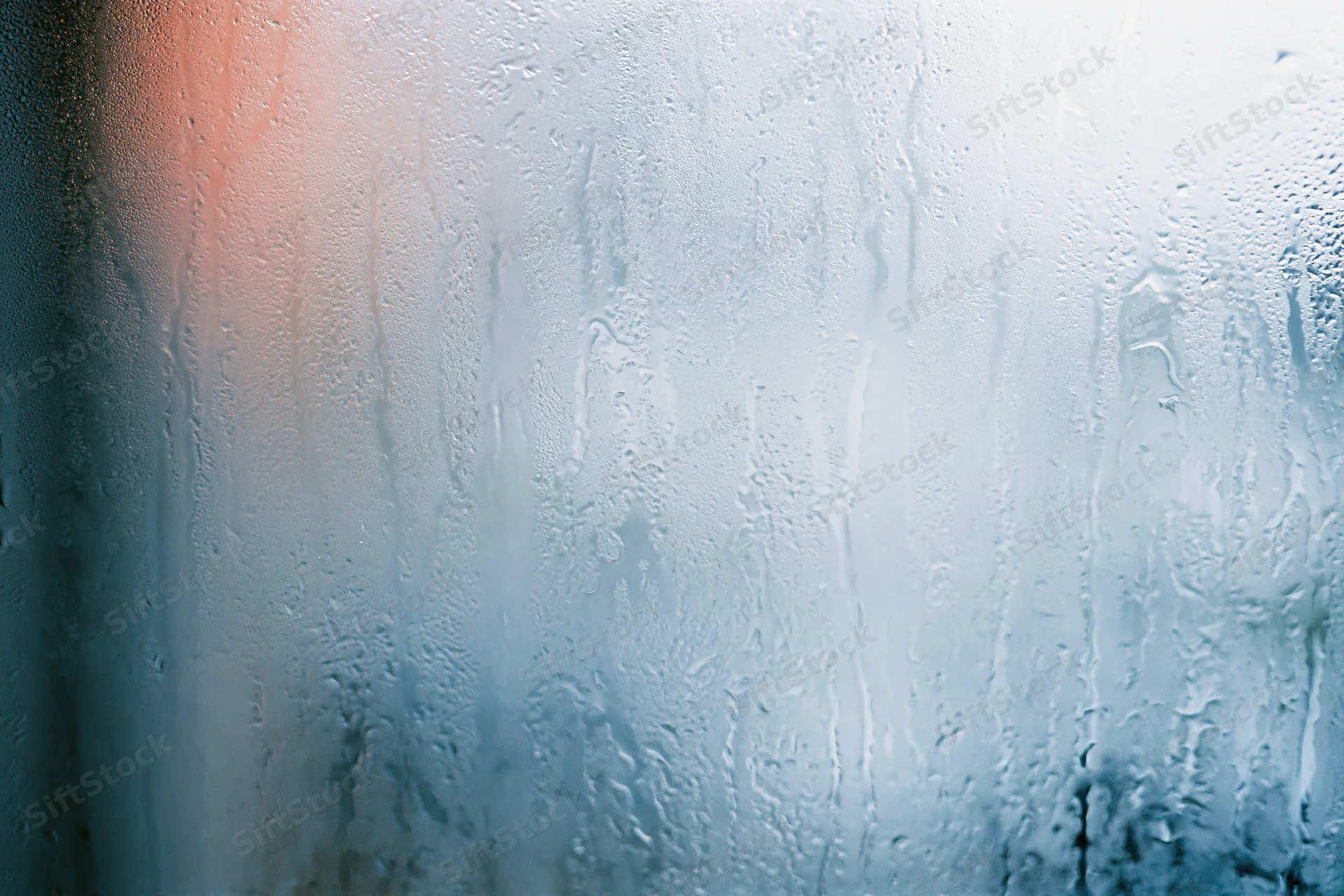 Close-up of condensation droplets and water streaks on a glass surface