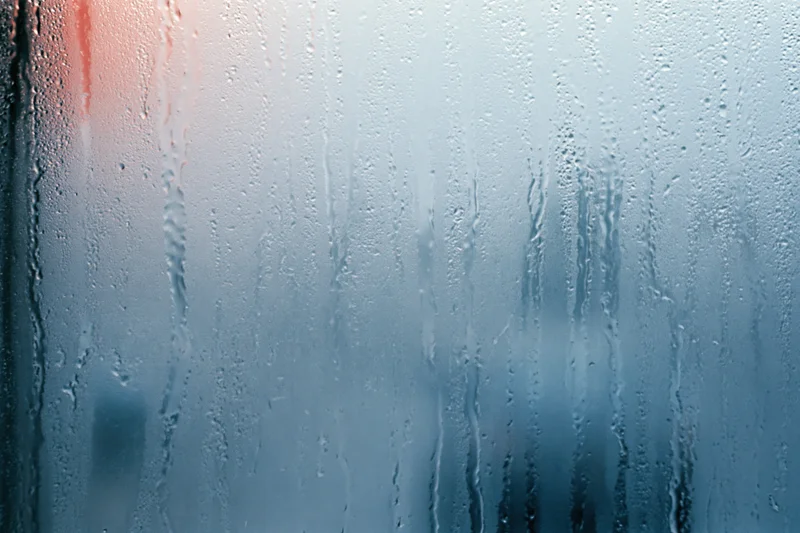 Close-up of condensation droplets and water streaks on a glass surface