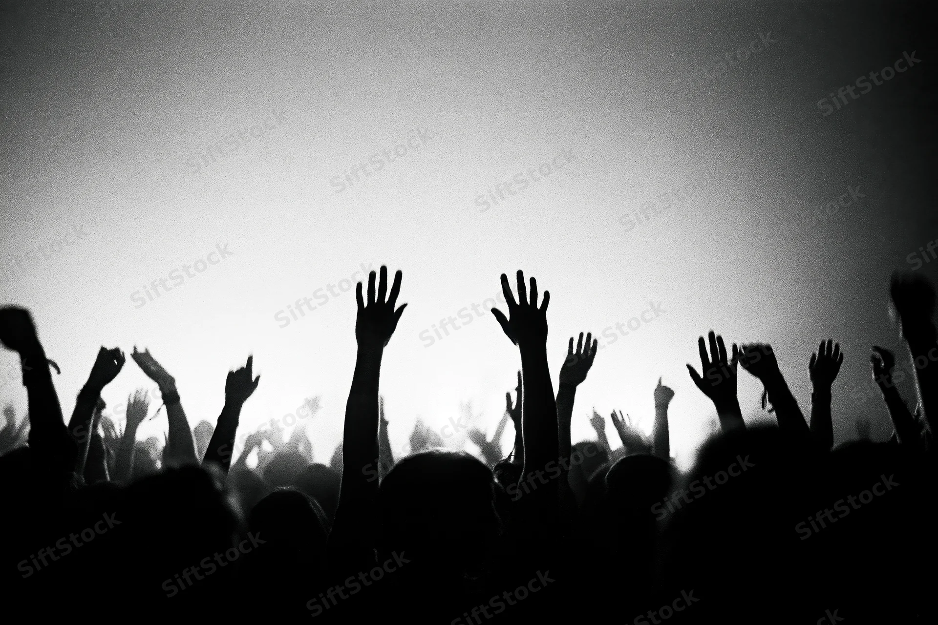 Silhouetted crowd with raised hands at a concert stage under bright backlighting