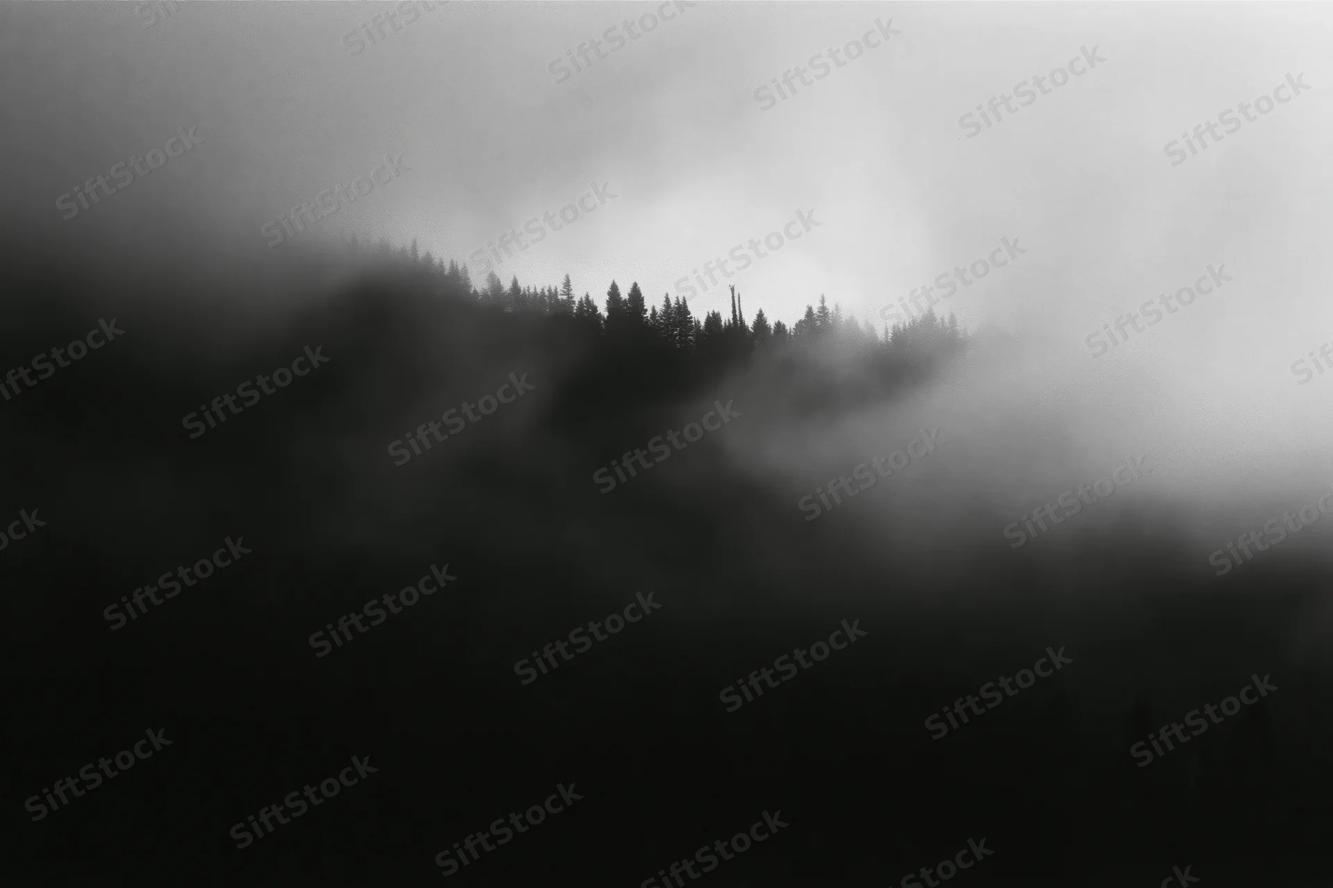 Dark forested mountain ridge silhouetted against swirling low fog