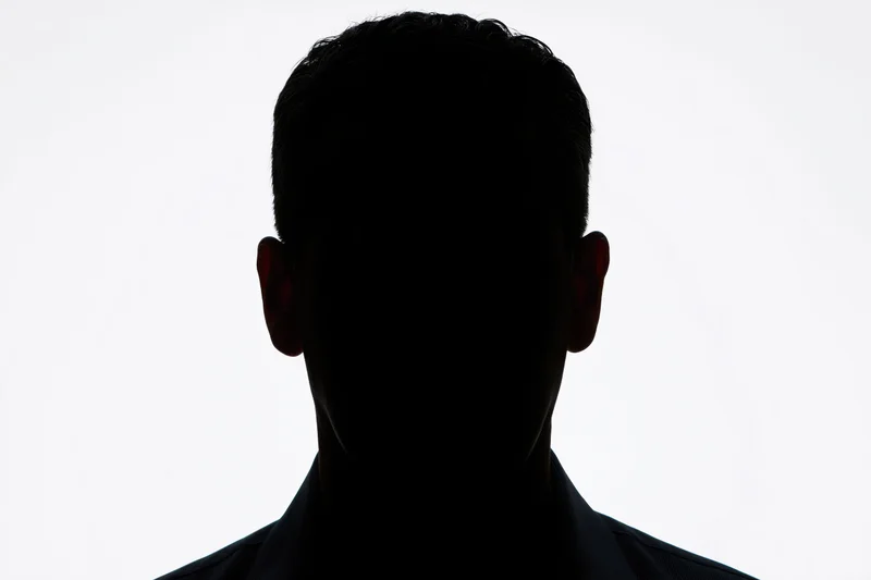 Silhouette of a man's head and shoulders facing forward against white background