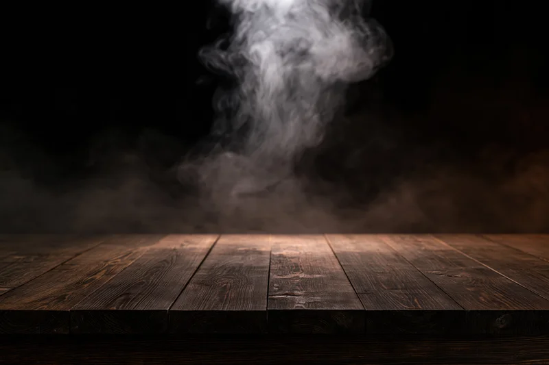 Dark wooden table surface with rising smoke against black background