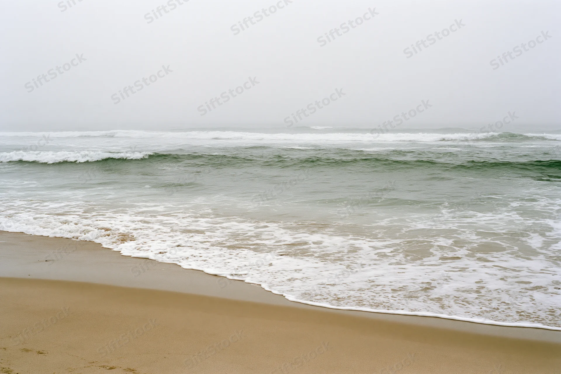 Gentle waves breaking onto a sandy beach under an overcast sky