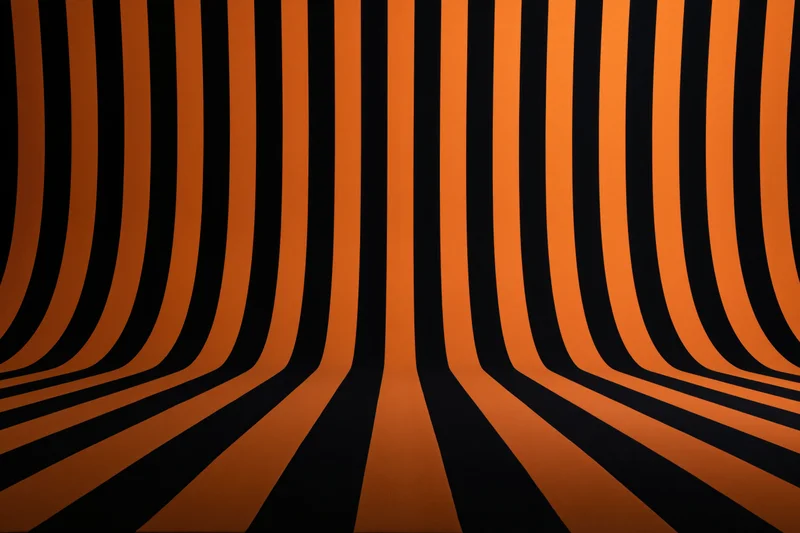 Curved orange and black stripes creating an infinite tunnel effect in a studio backdrop