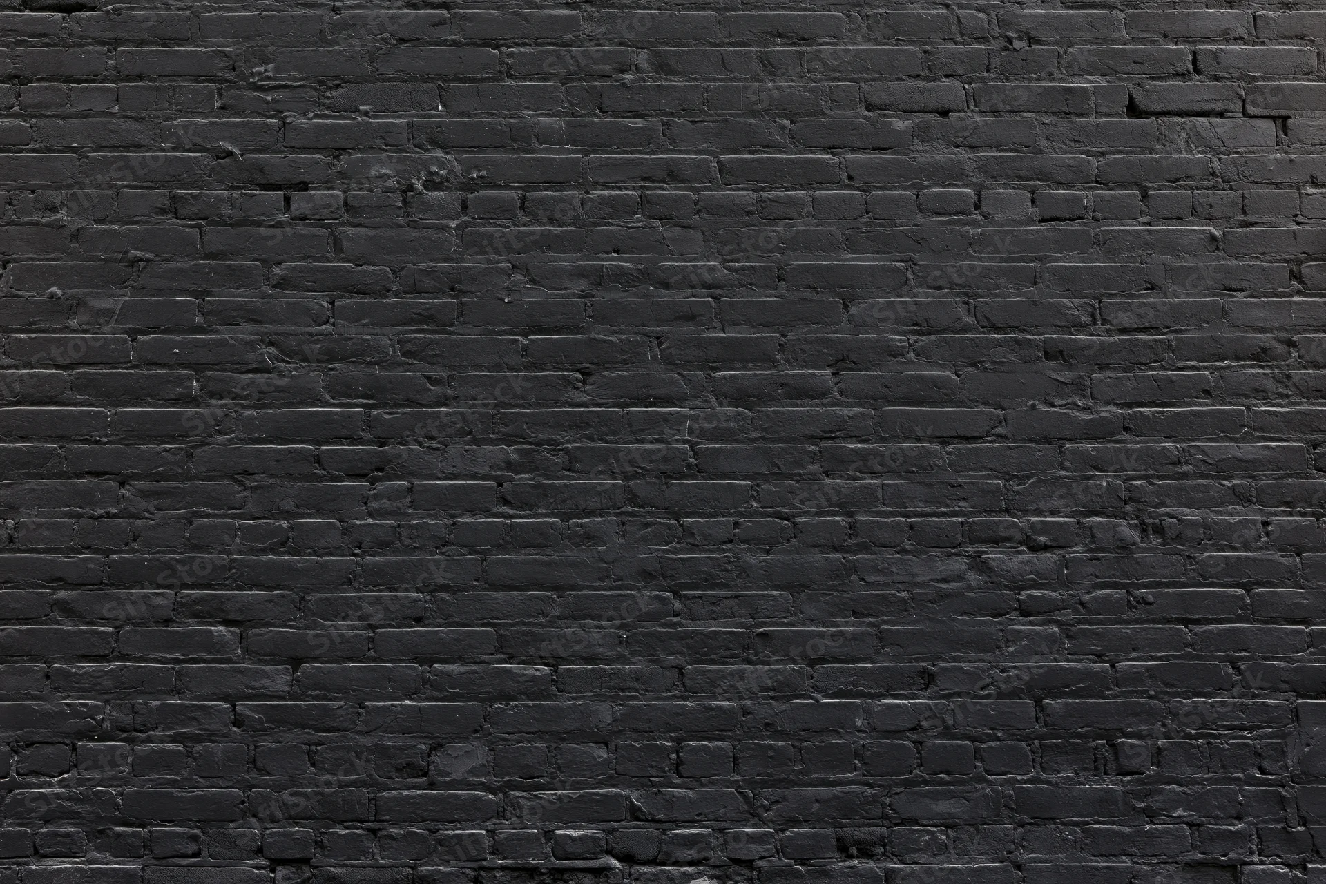 Black brick wall filling the frame with aged texture and mortar lines