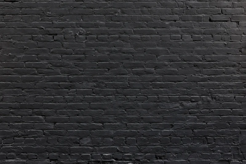 Black brick wall filling the frame with aged texture and mortar lines