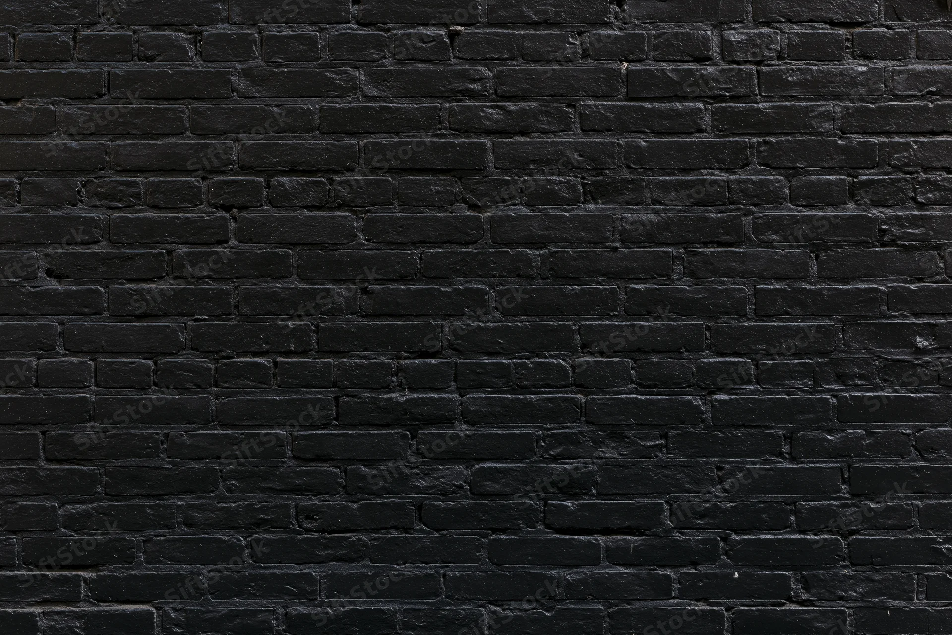 Black aged brick wall filling the frame as a textured surface