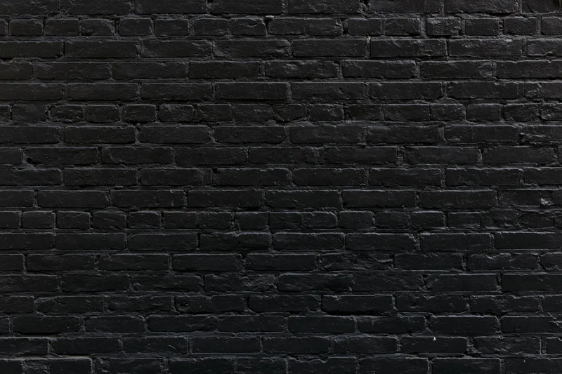 Black aged brick wall filling the frame as a textured surface