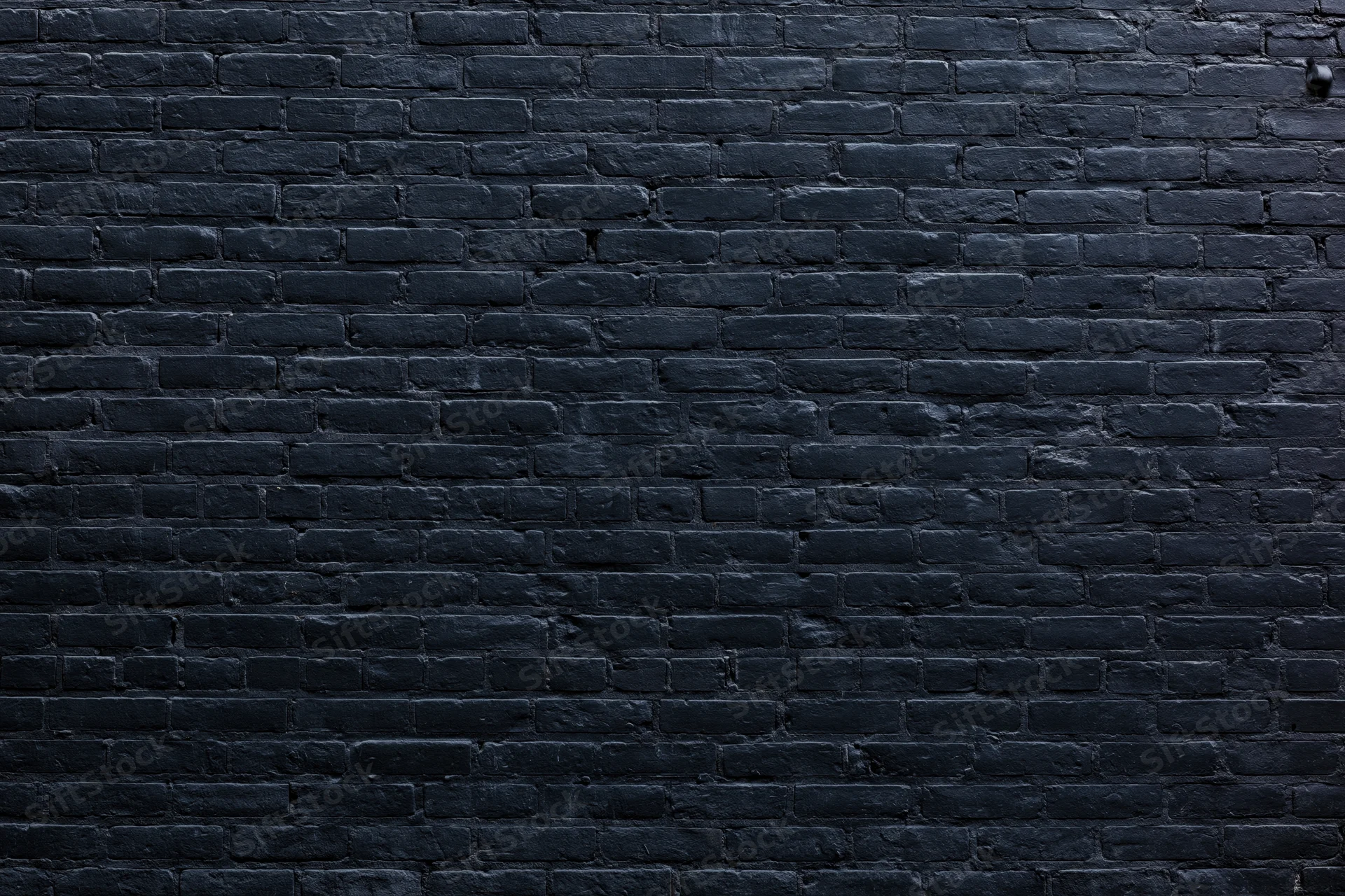 Black aged brick wall filling the frame as textured background