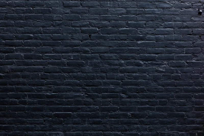 Black aged brick wall filling the frame as textured background