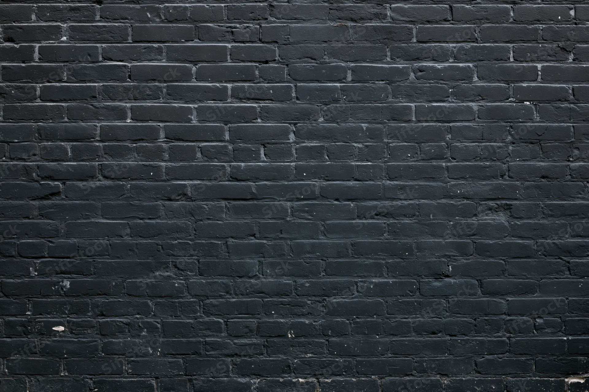 Black brick wall filling the frame with aged texture and mortar lines