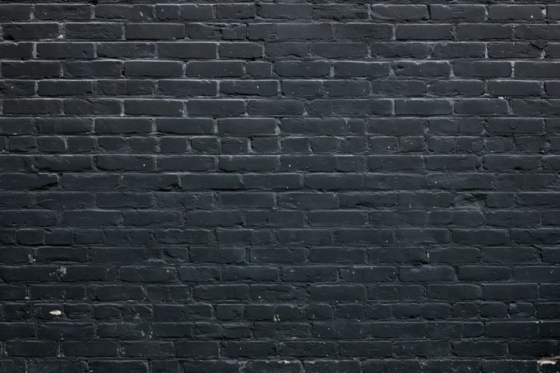Black brick wall filling the frame with aged texture and mortar lines