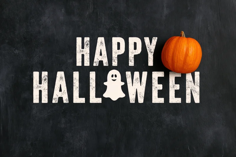 Flat lay halloween greeting card design with happy halloween text and pumpkin on black surface