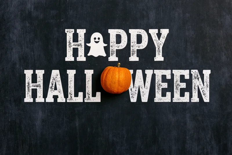 Flat lay halloween greeting card design with happy halloween text and pumpkin on black surface