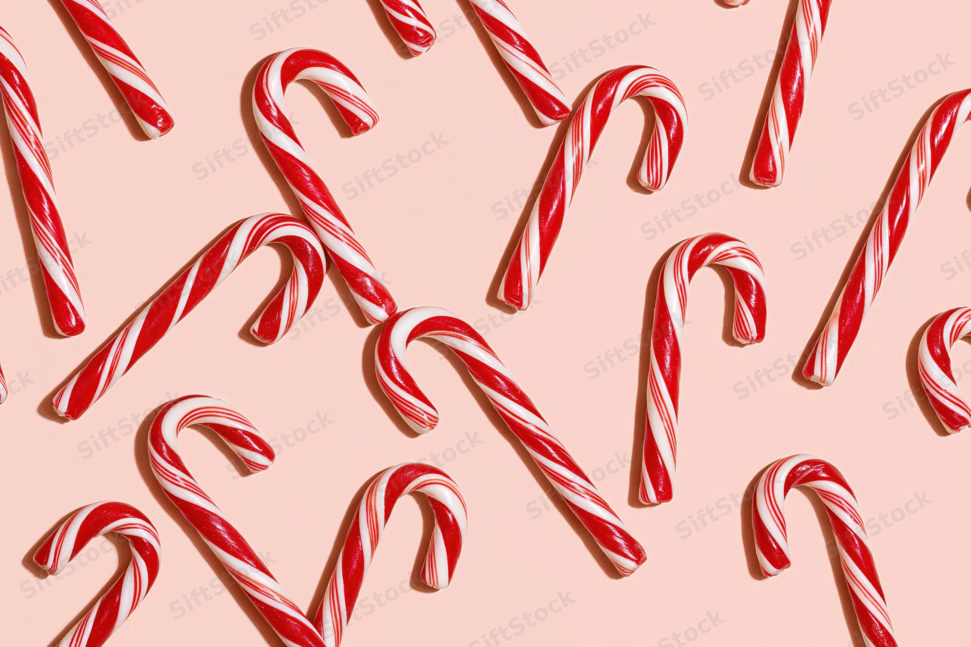 Candy canes arranged in scattered pattern on pastel peach background