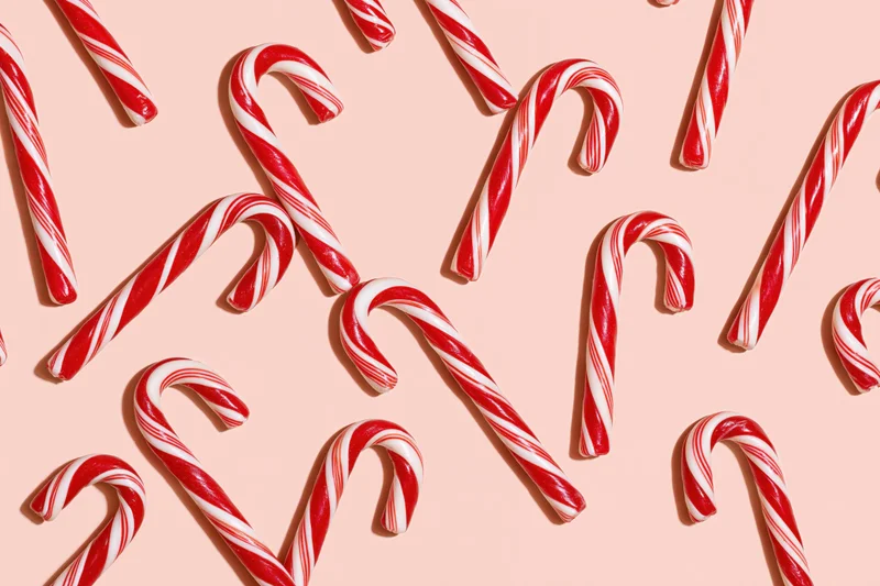Candy canes arranged in scattered pattern on pastel peach background