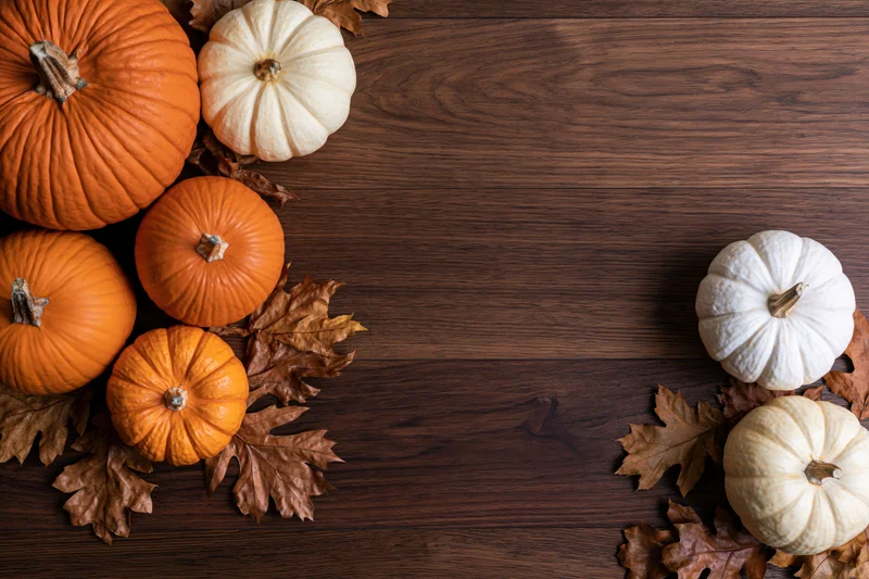 Pumpkins and autumn leaves arranged on a wooden table with copyspace