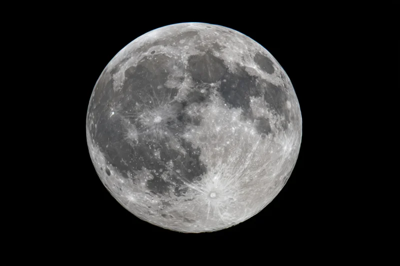 Full moon centered against pure black night sky in close-up view